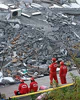 Rescue workers wait beside a collapsed furniture shop in Pingtung, southern Taiwan, 27 December 2006. A major earthquake measuring magnitude 7.1 rocked Taiwan 26 December, geologists said, killing one person while at least 29 others were wounded, officials said. Photo courtesy AFP.