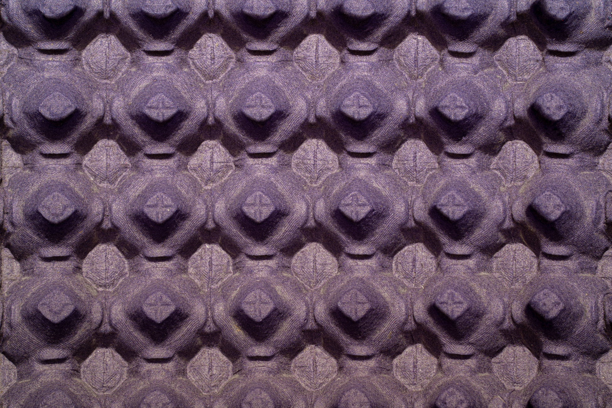 Close-up view of a textured purple egg carton surface with a repeating pattern.